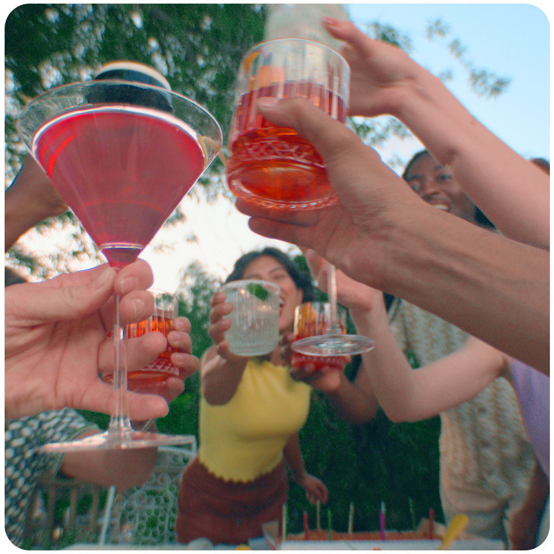 Seven people holding different cocktails up including a Ketel One Cosmopolitan, Astral Margarita, Ketel One Espresso Martini, and a Tanqueray Negroni.