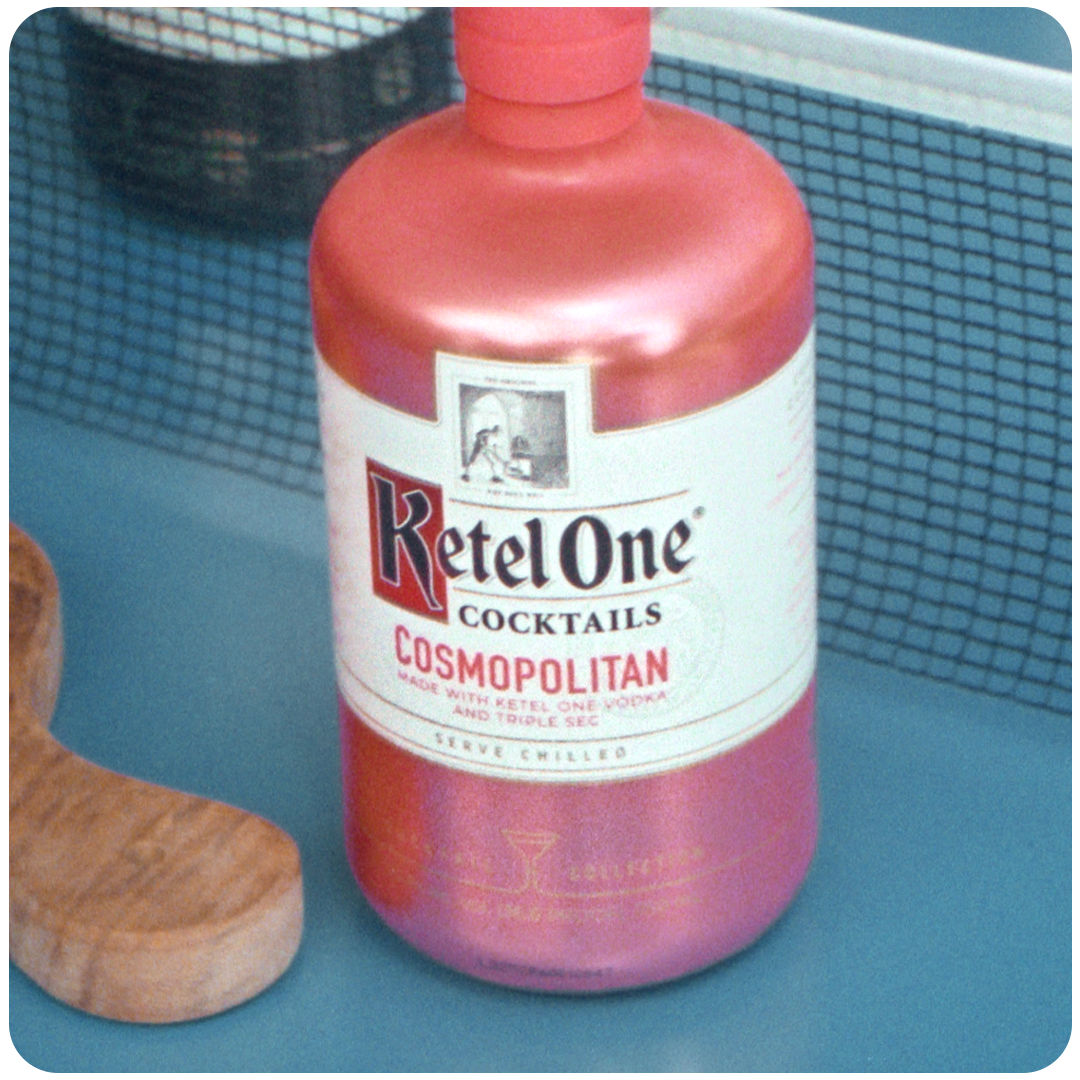 Ketel One pre-mixed cosmopolitan cocktail on a table next to a cutting board